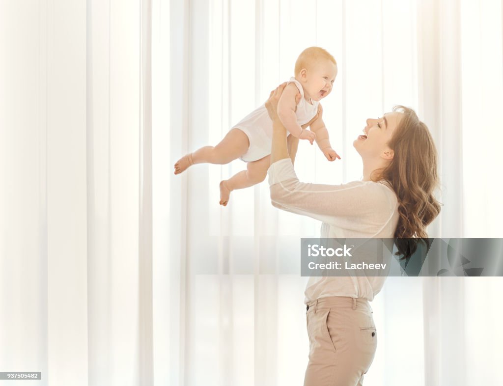 Mãe com um bebê nos braços dela joga contra a janela - Foto de stock de Bebê royalty-free