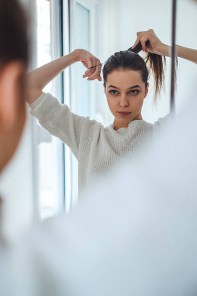 istock Girl looking in the mirror while tying ponytail 937523622