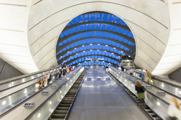 les personnes qui font la navette sur des escalators descendez à la station de métro, londres, angleterre - canary wharf railway station photos et images de collection