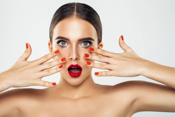 Beauty brunette woman with perfect makeup. Glamour girl. Red lips and nails. Perfect eyebrows. Skin care foundation. Beauty girls face isolated on green background. Fashion photo