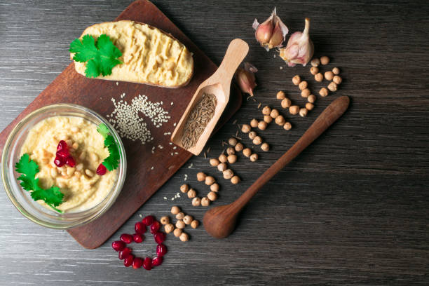 istock Hummus or houmous, appetizer made of mashed chickpeas with tahini, citron, garlic, olive oil, parsley, cumin and cedar nuts on wooden table, pomegranate. Healthy lifestyle, eating right concept 937544794