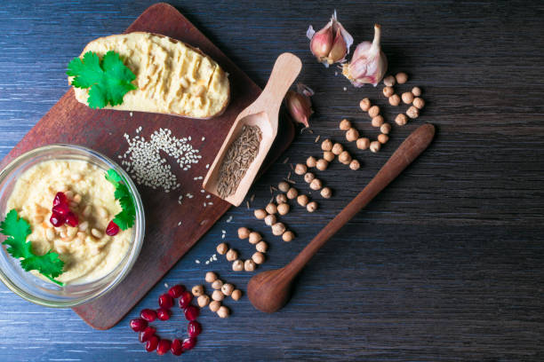 istock Hummus or houmous, appetizer made of mashed chickpeas with tahini, citron, garlic, olive oil, parsley, cumin and cedar nuts on wooden table, pomegranate. Healthy lifestyle, eating right concept 937546984