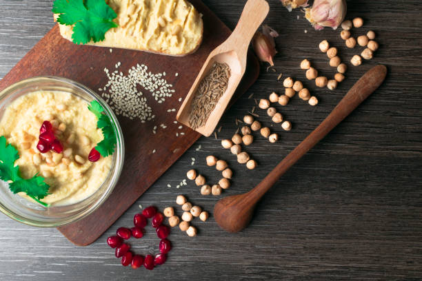 istock Hummus or houmous, appetizer made of mashed chickpeas with tahini, citron, garlic, olive oil, parsley, cumin and cedar nuts on wooden table, pomegranate. Healthy lifestyle, eating right concept 937547122
