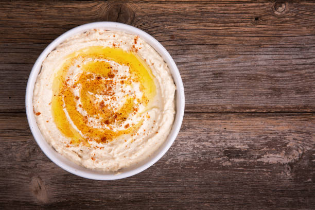 Bowl of hummus with olive oil and paprika A bowl of fresh hummus, drizzled with olive oil and paprika, over old wood background. hummus stock pictures, royalty-free photos & images