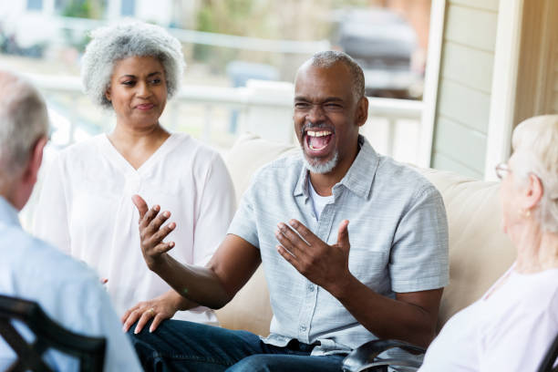 istock Senior man enjoys fun with friends on front porch 937553160