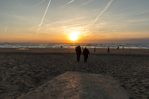 Man and woman walking on beach at sunset. Katwijk aan Zee. Netherlands