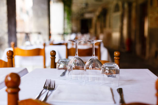 istock Empty inverted glasses on a wooden table with white tablecloth in a restaurant 937555976