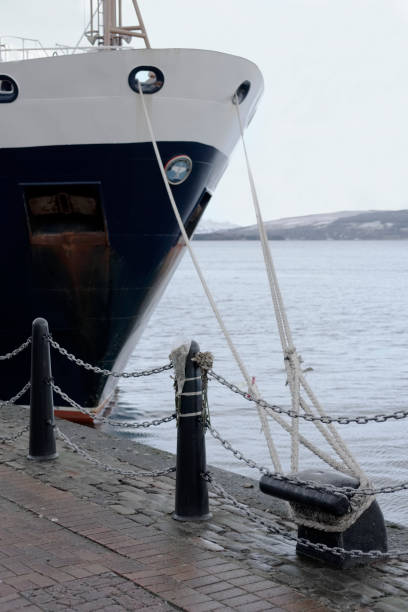 Ship front anchor rope line tied to dock harbour with rope knot for sailors