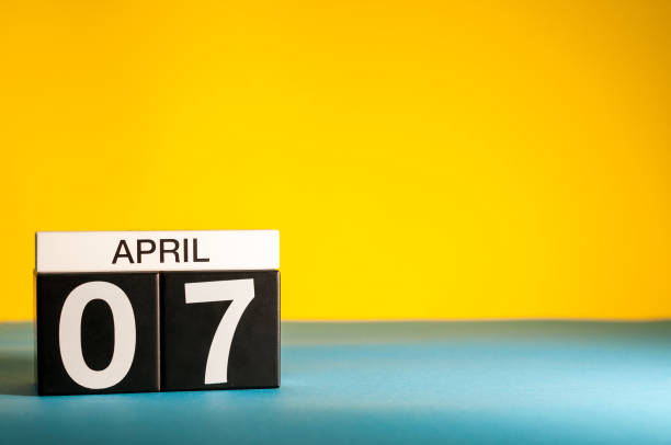 istock April 7th. Day 7 of april month, calendar on table with yellow background. Spring time, empty space for text 937577030