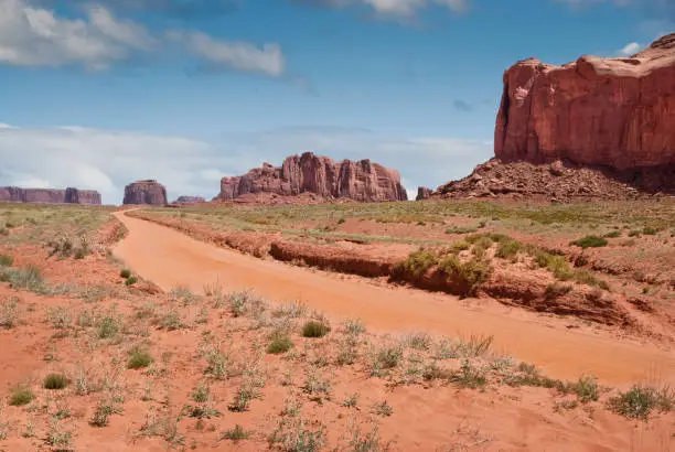 A dirt road leads toward Merrick Butte at Monument Valley Tribal Park in Arizona, USA.