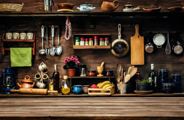 Photo of Actual rustic kitchen with utensils for cooking. Table at the foreground with copy space
