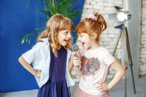 dwoje szczęśliwych małych dzieci śpiewa piosenkę w karaoke. koncepcja jest - happy kid audio zdjęcia i obrazy z banku zdjęć