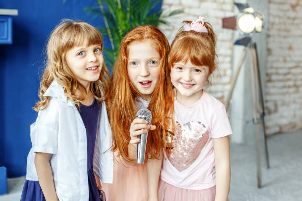istock Three kids sing a song in a microphone. Group. The concept is ch 937599110