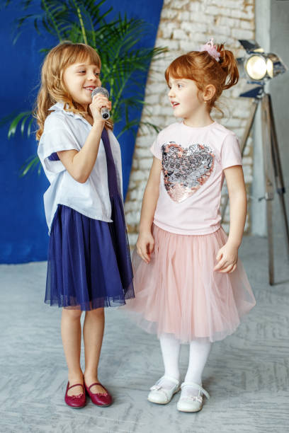 two young children sing a song on a microphone. group. the conce - circular skirt fotos imagens e fotografias de stock