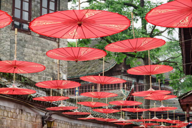 Rows of traditional Chinese red umbrellas at street, Fenghuang Fenghuang, China - September 22, 2017: Scenic rows of traditional oriental Chinese red umbrellas at narrow street in Phoenix Ancient Town (Fenghuang County) in evening. phenix stock pictures, royalty-free photos & images