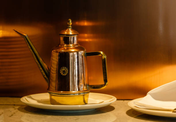 istock Old and antique vintage copper water pitcher or coffee pot with handcrafted brass handle on aged wood boards serving table in an ancient historic house 937688930