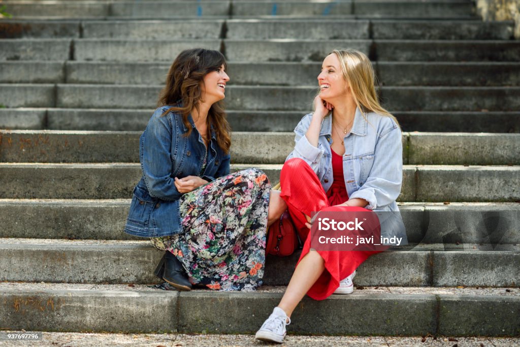 Zwei junge Frauen redeten und lachten über städtische Schritte - Lizenzfrei Reden Stock-Foto