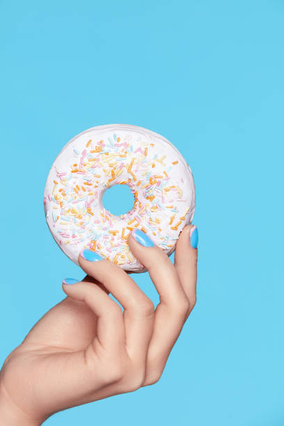 istock Manicure. Hand With Blue Nails Holding Donut 937698012