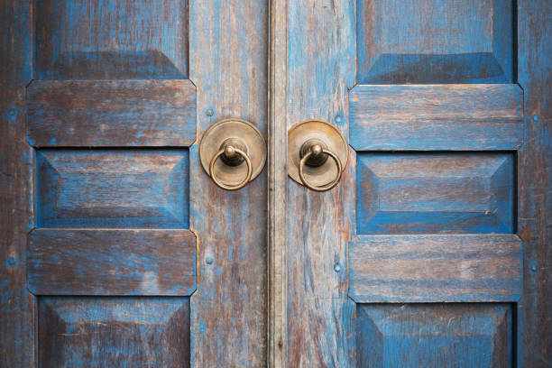 Blue painted aged worn wooden door with metal circle handle. Entrance detail