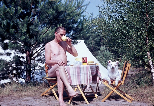 Baltic Sea, Germany, 1960. A camper, in company with his dog, enjoys a cup of coffee in front of his tent.