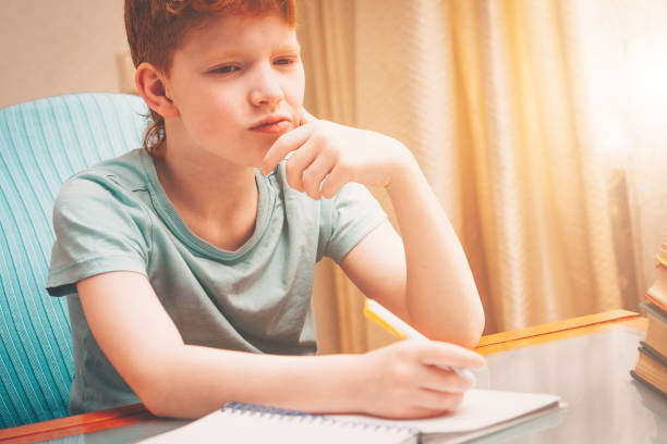 istock Red-haired boy pondered the task of doing homework 937732318