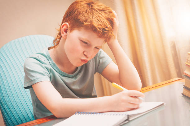 istock Red-haired boy pondered the task of doing homework 937732896