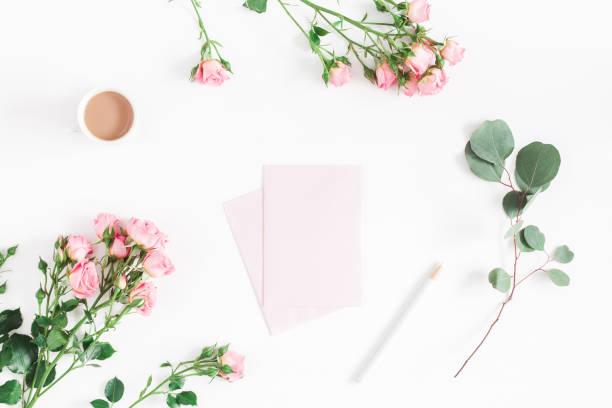 istock Desk rose flowers, eucalyptus branch, pink paper blank. Flat lay, 937735636