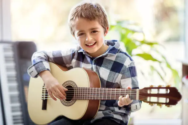 Photo of Boy playing acoustic guitar