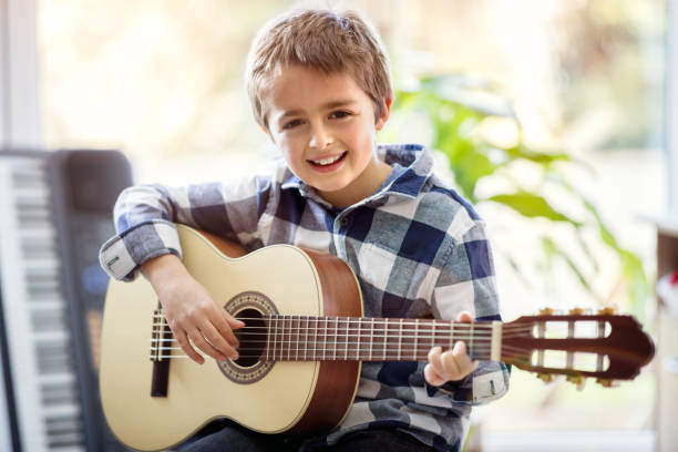 boy playing acoustic guitar - practicing piano child playing imagens e fotografias de stock