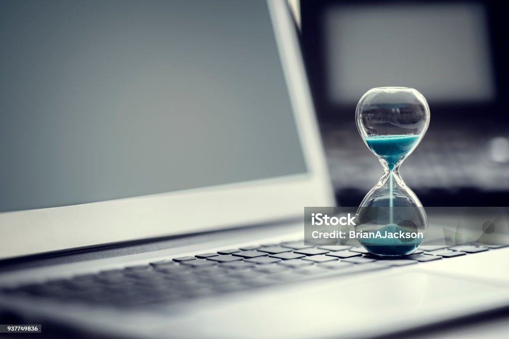 Reloj de arena en el concepto de ordenador portátil para la gestión del tiempo - Foto de stock de Tiempo libre de derechos