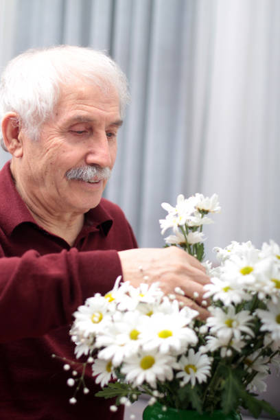 istock An old man arranging flowers 937775796