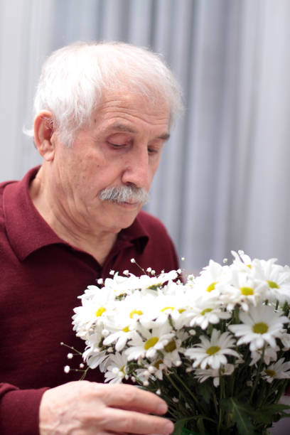 istock Old man looking at a bouquet of daisies 937777118