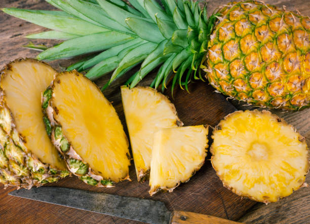 istock one solid and one sliced pineapples with knife on wooden background 937788406