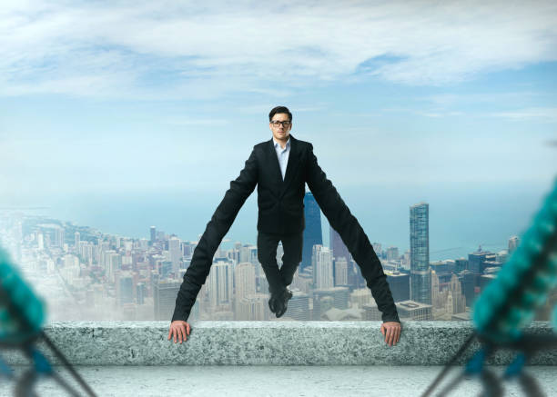istock Grasping businessman holds on to a roof edge 937791296
