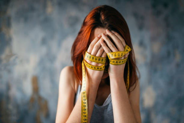 istock Woman covers face, hands tied with measuring tape 937791850