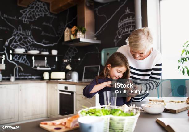 A Small Girl With Grandmother Cooking At Home Stock Photo - Download Image Now - Grandmother, Grandparent, Family