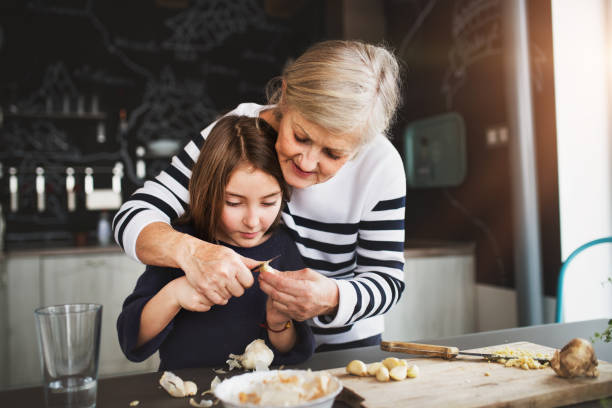 ein kleines mädchen mit großmutter zu hause kochen. - grandmother and grandaughter stock-fotos und bilder