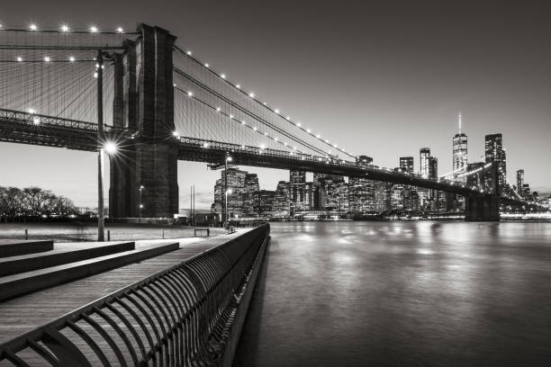Brooklyn Bridge Park boardwalk Lower Manhattan, East River, and the Brooklyn Bridge in Black & White. Brooklyn, New York City Brooklyn Bridge Park boardwalk in evening with the skyscrapers of Lower Manhattan, East River, and the Brooklyn Bridge in Black & White. Brooklyn, New York City east river new york city photos stock pictures, royalty-free photos & images