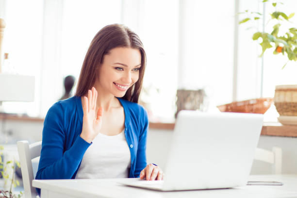 istock Hello there! Young cheerful lady is waving to the camera while having video call in light modern designed cafe, so happy and excited 937803128