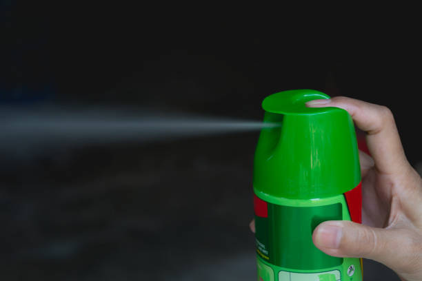 Hand holding mosquito spray. Human using mosquito spray from bottle. stock photo