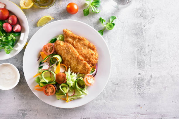 Vegetable salad and schnitzel Tasty healthy vegetable salad and schnitzel on stone background with copy space. Top view, flat lay schnitzel stock pictures, royalty-free photos & images