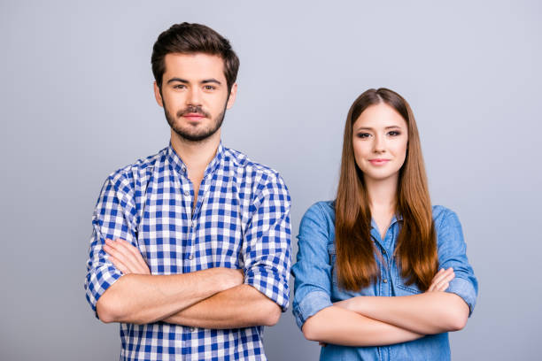 istock Two cheerful young lovers are looking at the camera and smile, standing both with crossed hands, wearing casual clothes, on the pure background 937818922