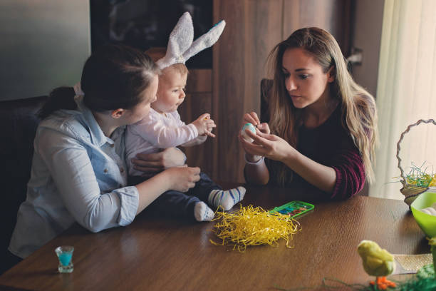 istock Young mother and her baby having fun while painting eggs for Easter 937821640
