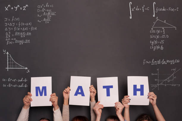Classroom and chalkboard with formulas and numbers.Math and algebra concept. Four persons holding placards with letters MATH stock photo