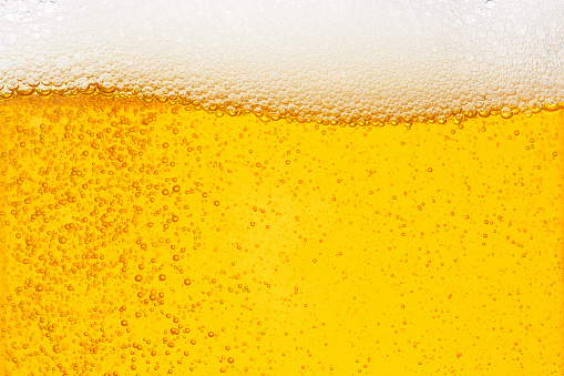 Pouring beer with bubble froth in glass for background on front view wave curve shape