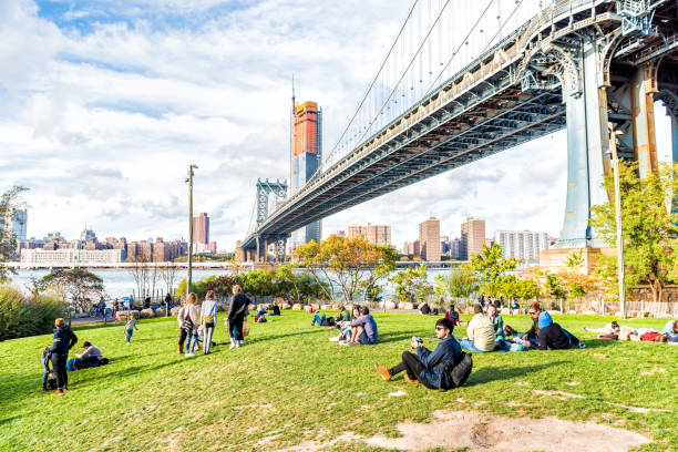 Dumbo outside exterior outdoors in NYC New York City, people in green, urban Main Street Park, cityscape skyline and bridge with east river Brooklyn, USA - October 28, 2017: Dumbo outside exterior outdoors in NYC New York City, people in green, urban Main Street Park, cityscape skyline and bridge with east river dumbo new york photos stock pictures, royalty-free photos & images