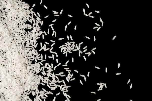 istock Pile of white raw rice splash isolated on black background on top view 937839502