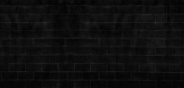 A long full frame color image of a rustic weathered and stained dark black wall abstract background.