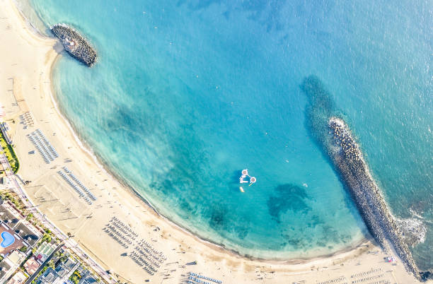 vista aerea della spiaggia della baia di los cristianos a tenerife con lettini e ombrelloni in miniatura - concetto di viaggio con paesaggio di meraviglia della natura nelle isole canarie spagna - filtro luminoso per le giornate calde - sky travel destinations tourism canary islands foto e immagini stock