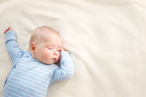 Baby sleeping covered with soft blanket little boy sleeping on soft white blanket headwear photos stock pictures, royalty-free photos & images